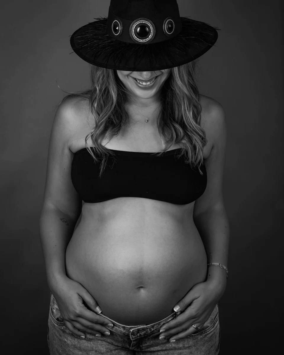 Retrato de embarazo en blanco y negro con sombrero.