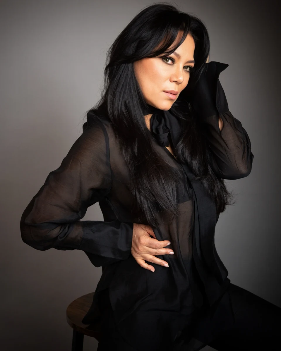 Retrato con ropa negra y una mano junto al cabello.