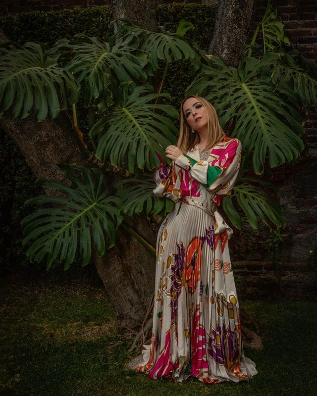 Retrato de cuerpo entero en un jardín, con vestido estampado.