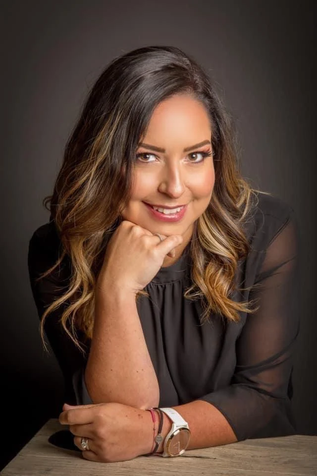 Retrato con vestido negro y manos sobre una mesa.