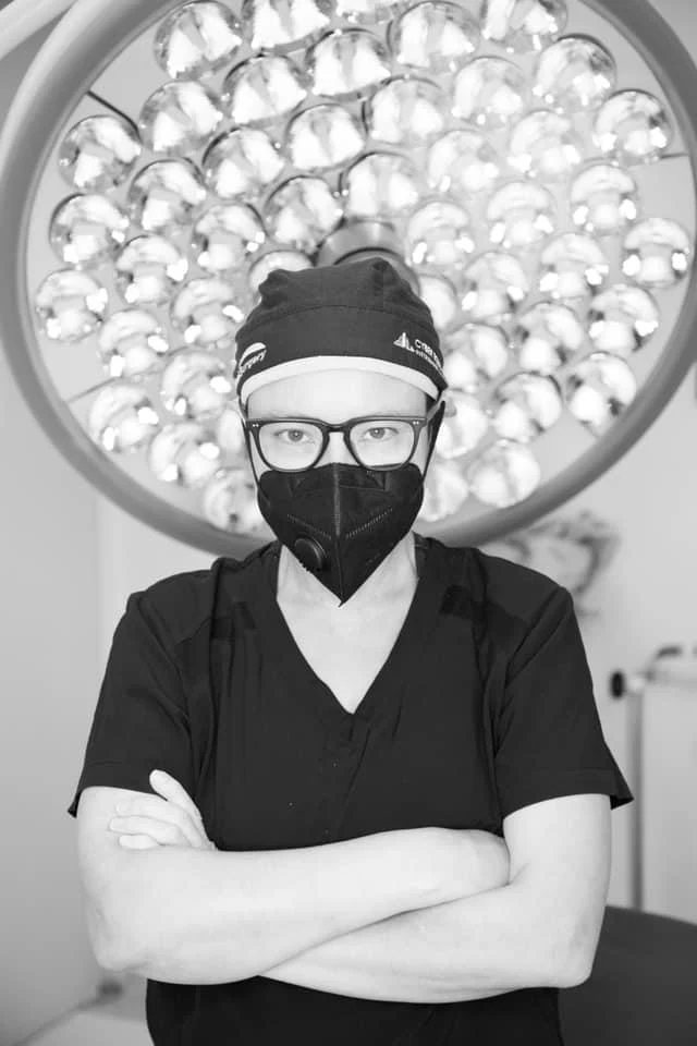 Retrato con uniforme quirúrgico bajo una lámpara.