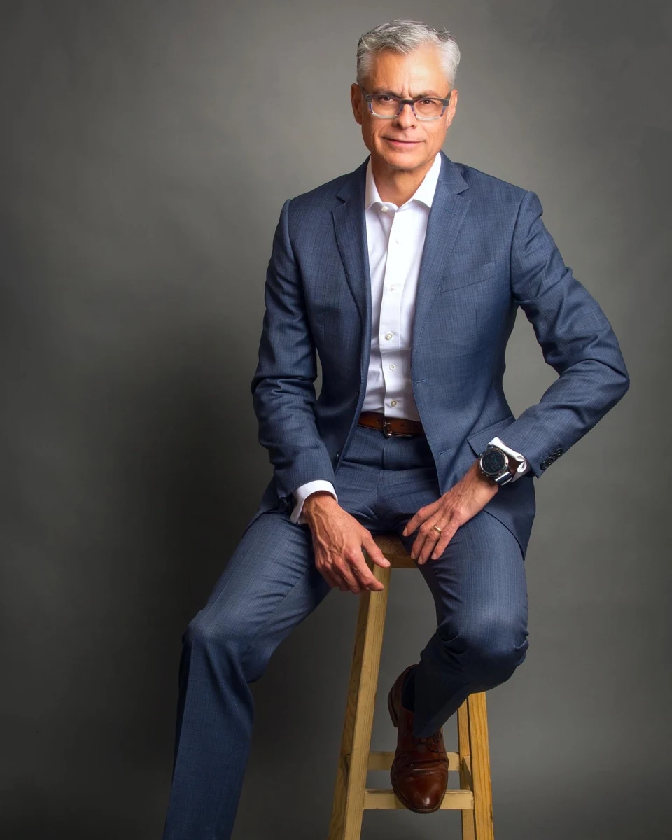Retrato masculino con traje azul sobre un banco.