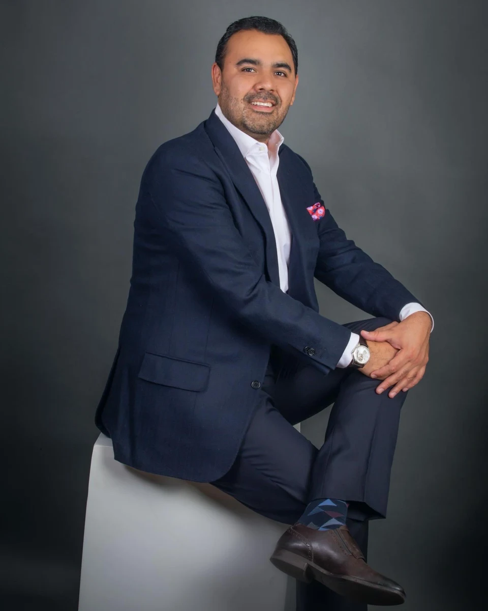 Retrato masculino con traje azul sentado de lado.